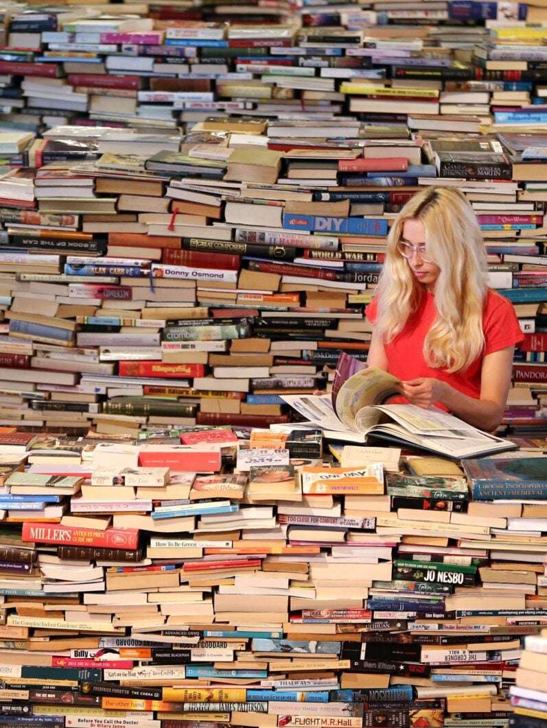 Woman reading surrounded by books