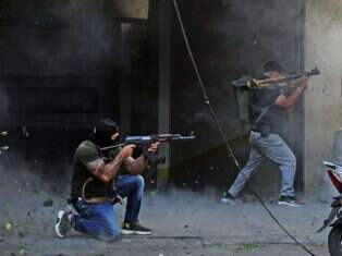 Shia fighters from Hezbollah and Amal take aim during clashes in a southern suburb of Beirut, on 14 October.