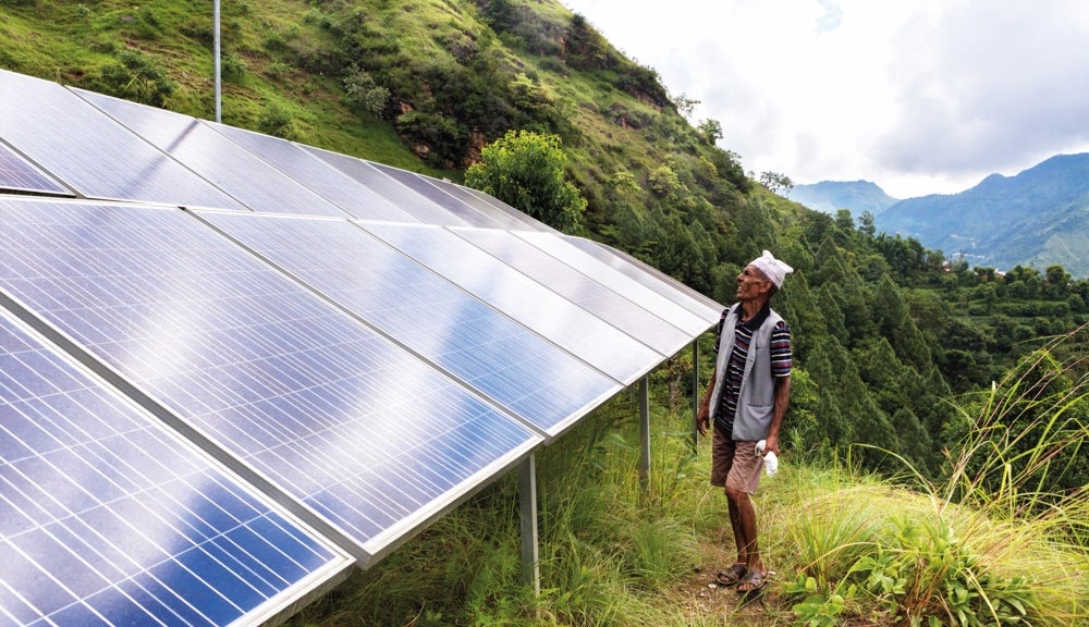 A man standing beside a solar-powered microgrid in Nepal