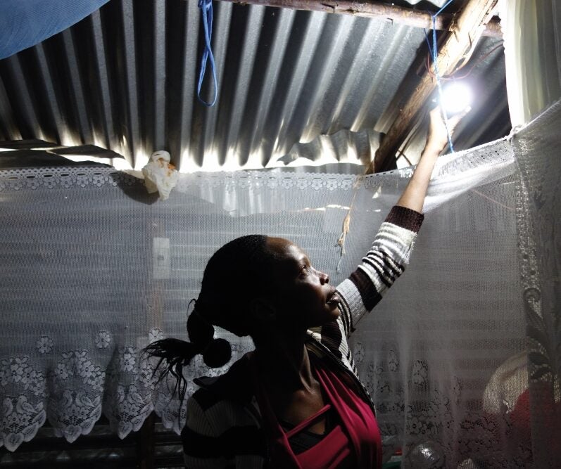 A woman turning on a light powered by a solar microgrid