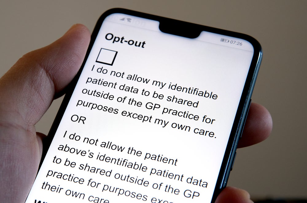 A hand clicking on an NHS data consent withdrawal form on their phone