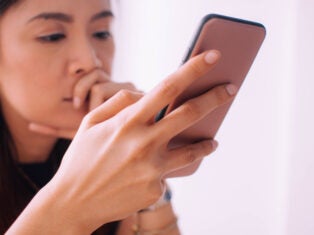 Woman using phone and looking unhappy