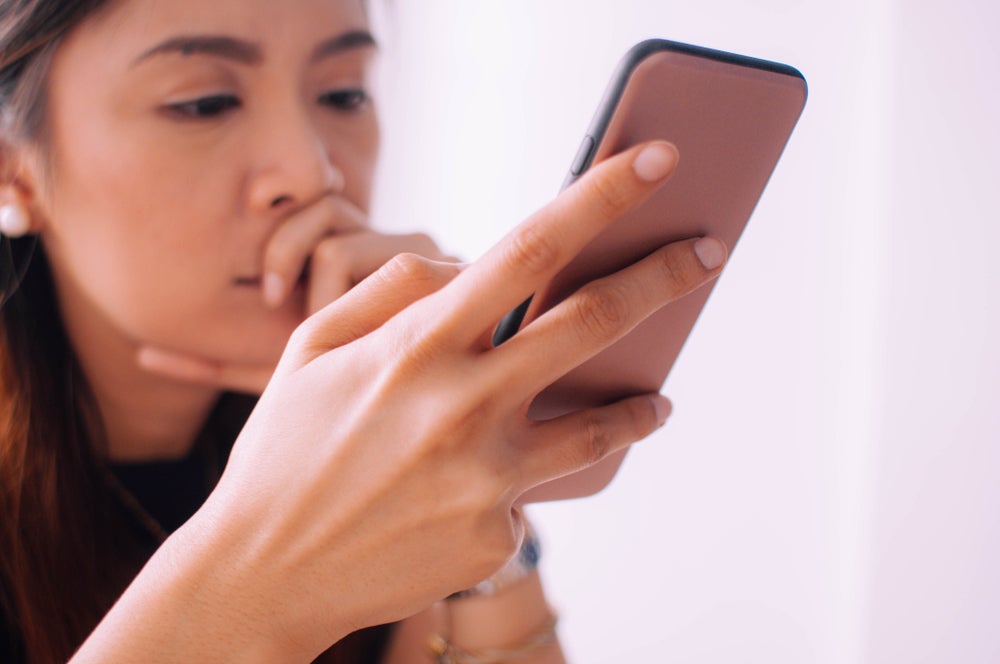 Woman using phone and looking unhappy