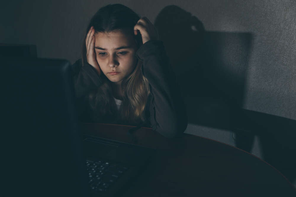 Teenage girl using a laptop looking upset