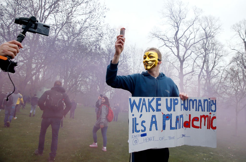 A protester with a flare poses holding a sign calling for people to "wake up" during a "World Wide Rally For Freedom" protest on March 20, 2021 in London, England.