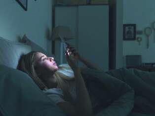 Woman looking at her phone while in bed