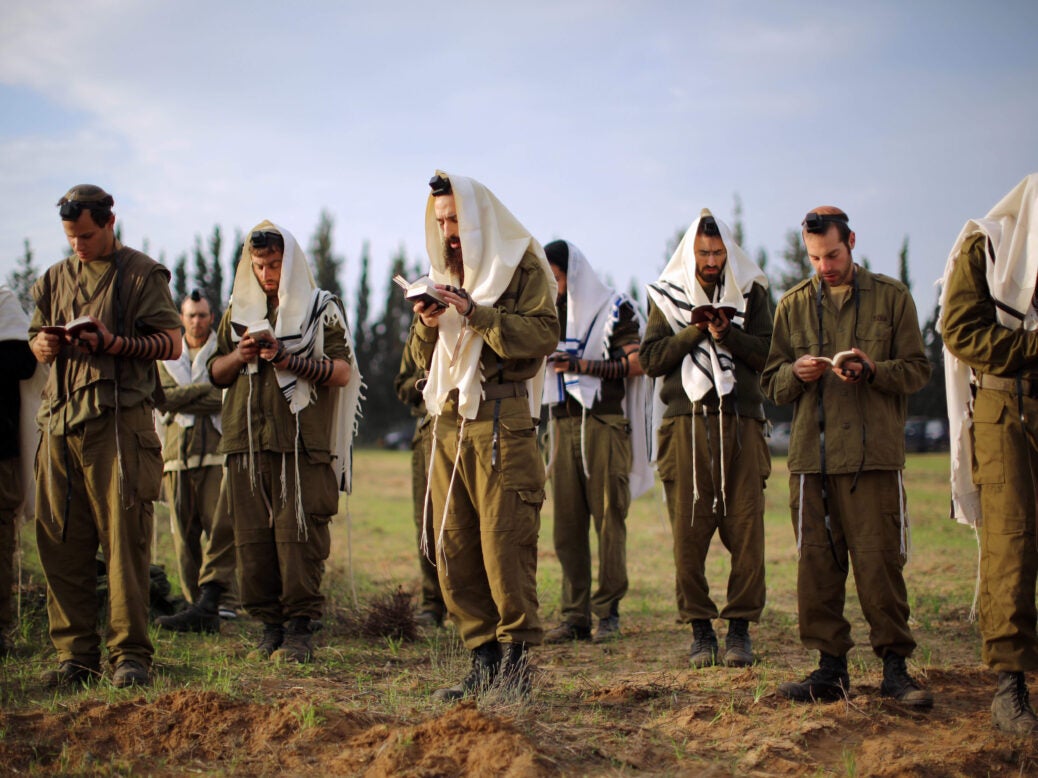 Israeli soldiers pray at dawn at an artillery emplacement